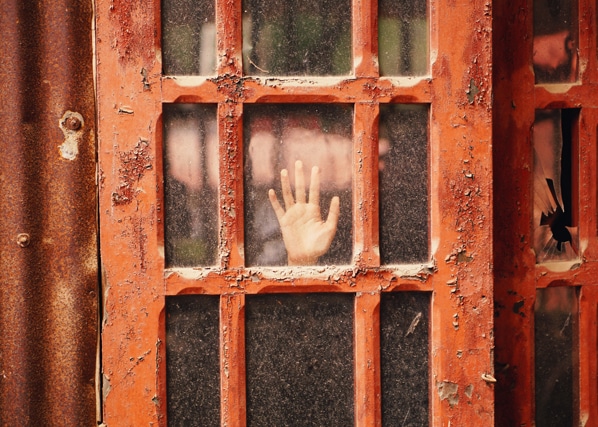 Hand pressed against a glass door by person suffering from emotional abuse before calling a therapist at MindSol Wellness Center in Sarasota, Florida