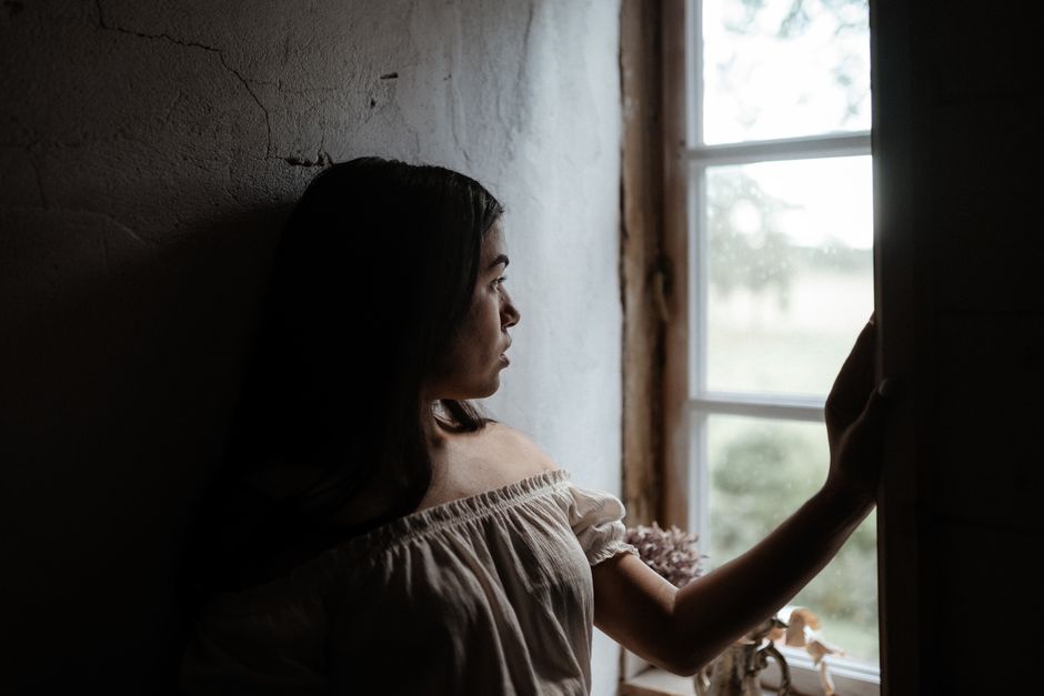 A woman sitting quietly by a window in a calm, reflective moment