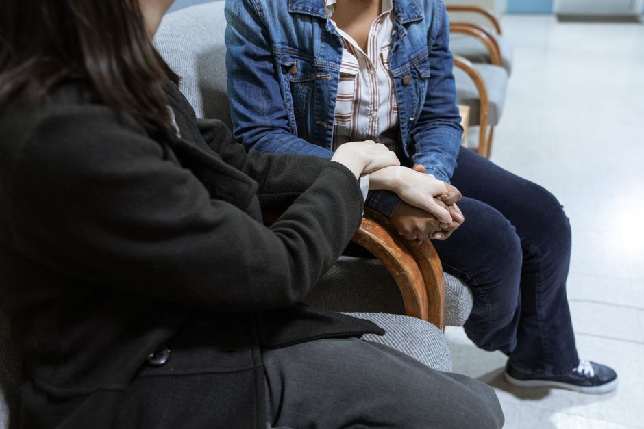 Two people sitting together, one offering comfort and support