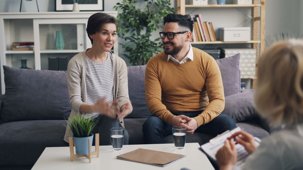 A couple talking with a counselor during a session in a bright room