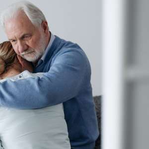 An older man comforting a woman with a hug during a difficult moment
