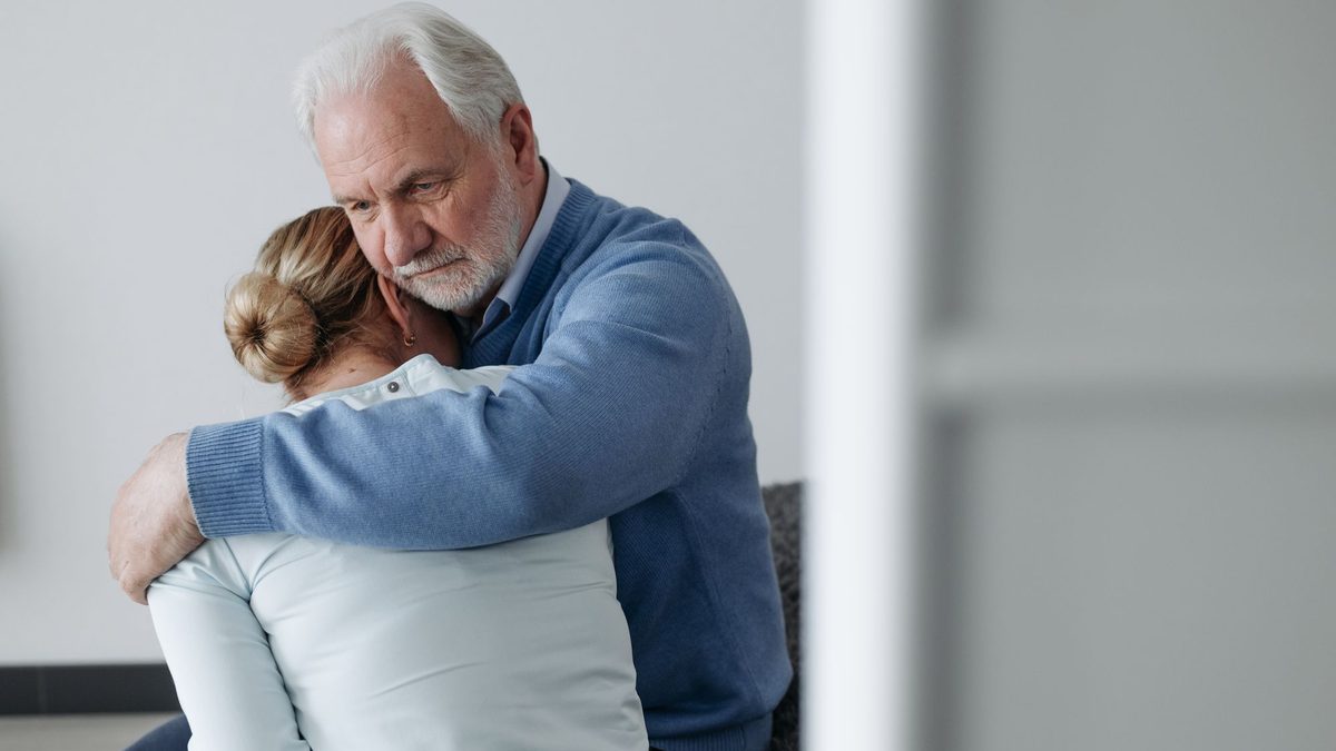 An older man comforting a woman with a hug during a difficult moment