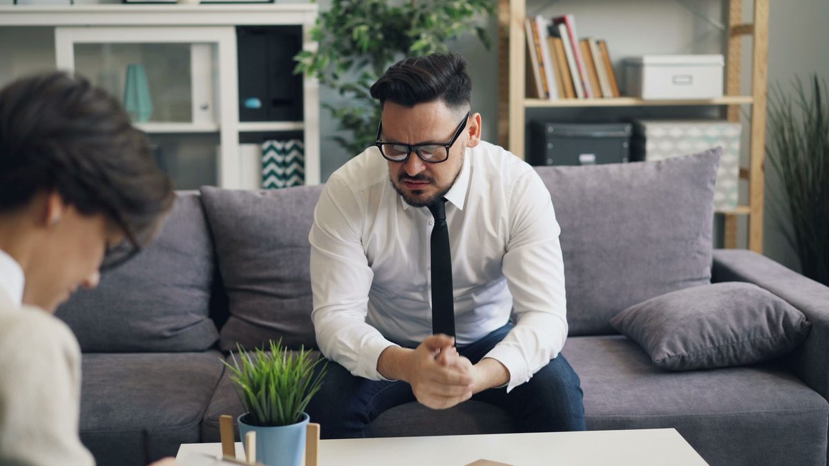 A man in work clothes talking with a counselor during a session