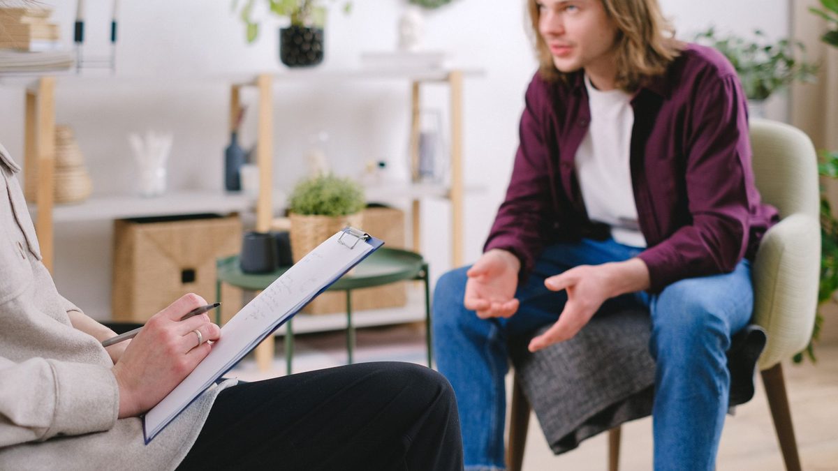 A man talking with a therapist who takes notes during a counseling session